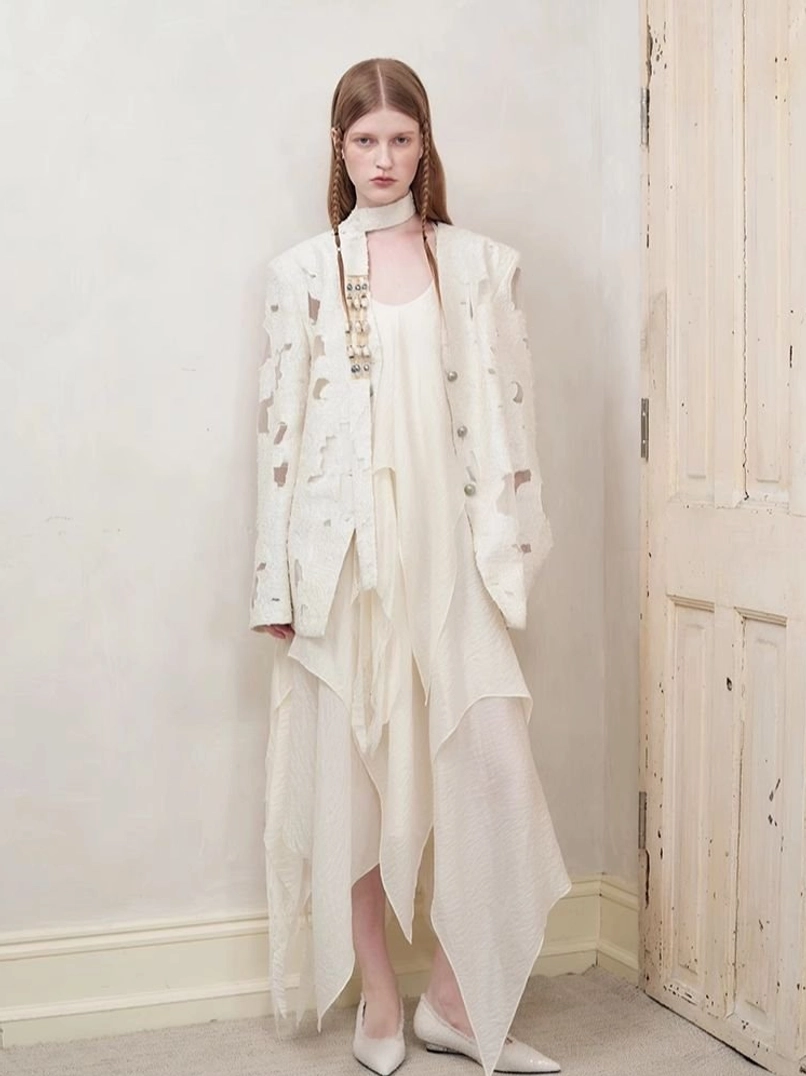 Distressed off-white cutout blazer women streetwear outfit with asymmetric dress beside vintage wooden door