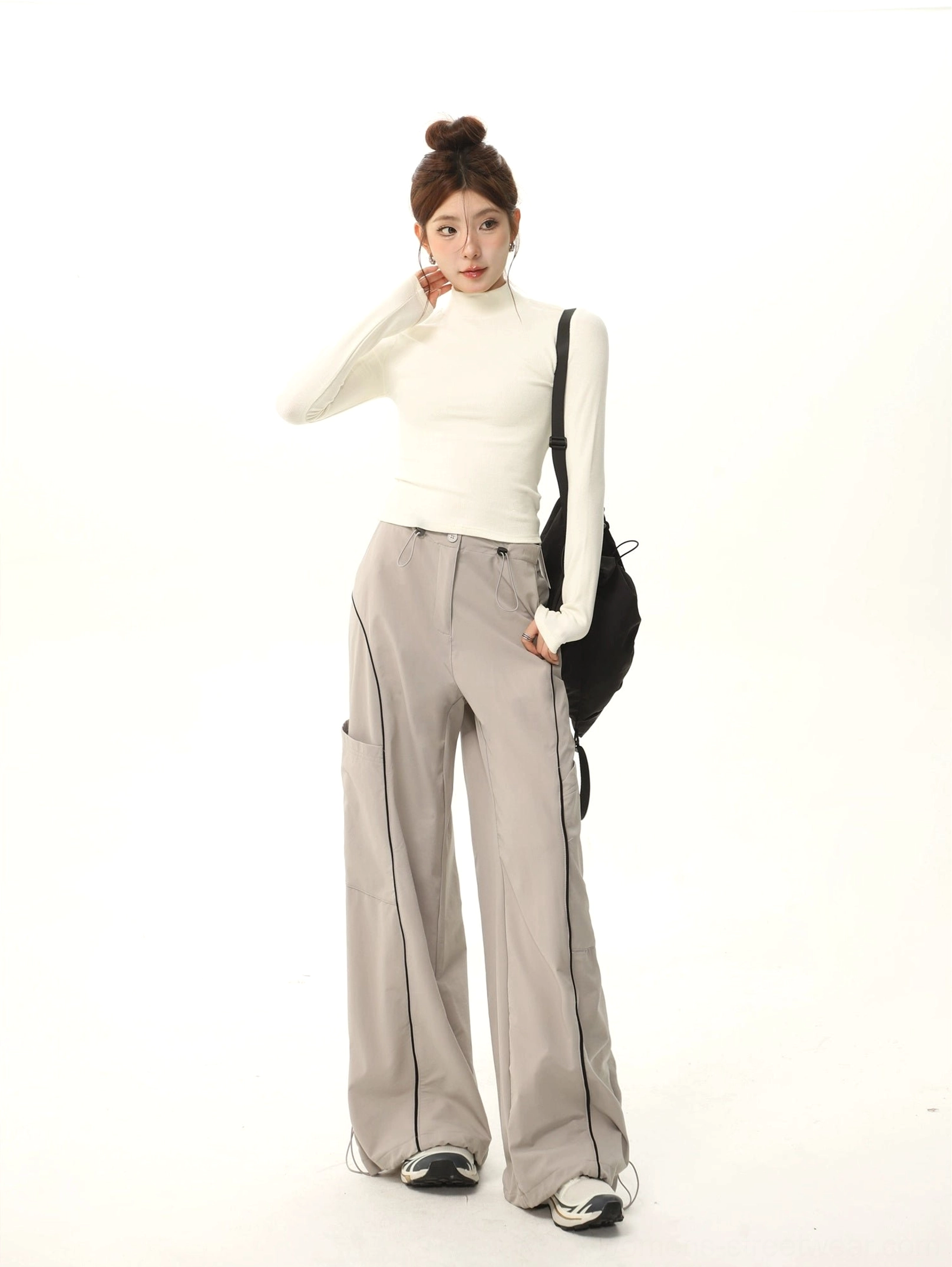 Off-white fitted mock neck long sleeve streetwear top shown from the side with grey cargo pants and black crossbody bag