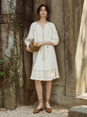 Off-white geometric embroidered balloon-sleeve shift midi dress front full-body view in a vintage stone courtyard