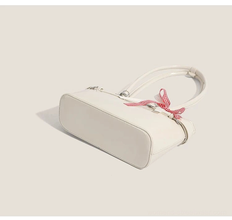 Off-white glossy faux leather baguette shoulder bag shown from a top-side view with red gingham bow and slim underarm profile