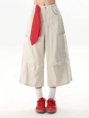 Side front view of off-white high-waisted cargo culottes featuring wide cropped legs and a red striped tie detail