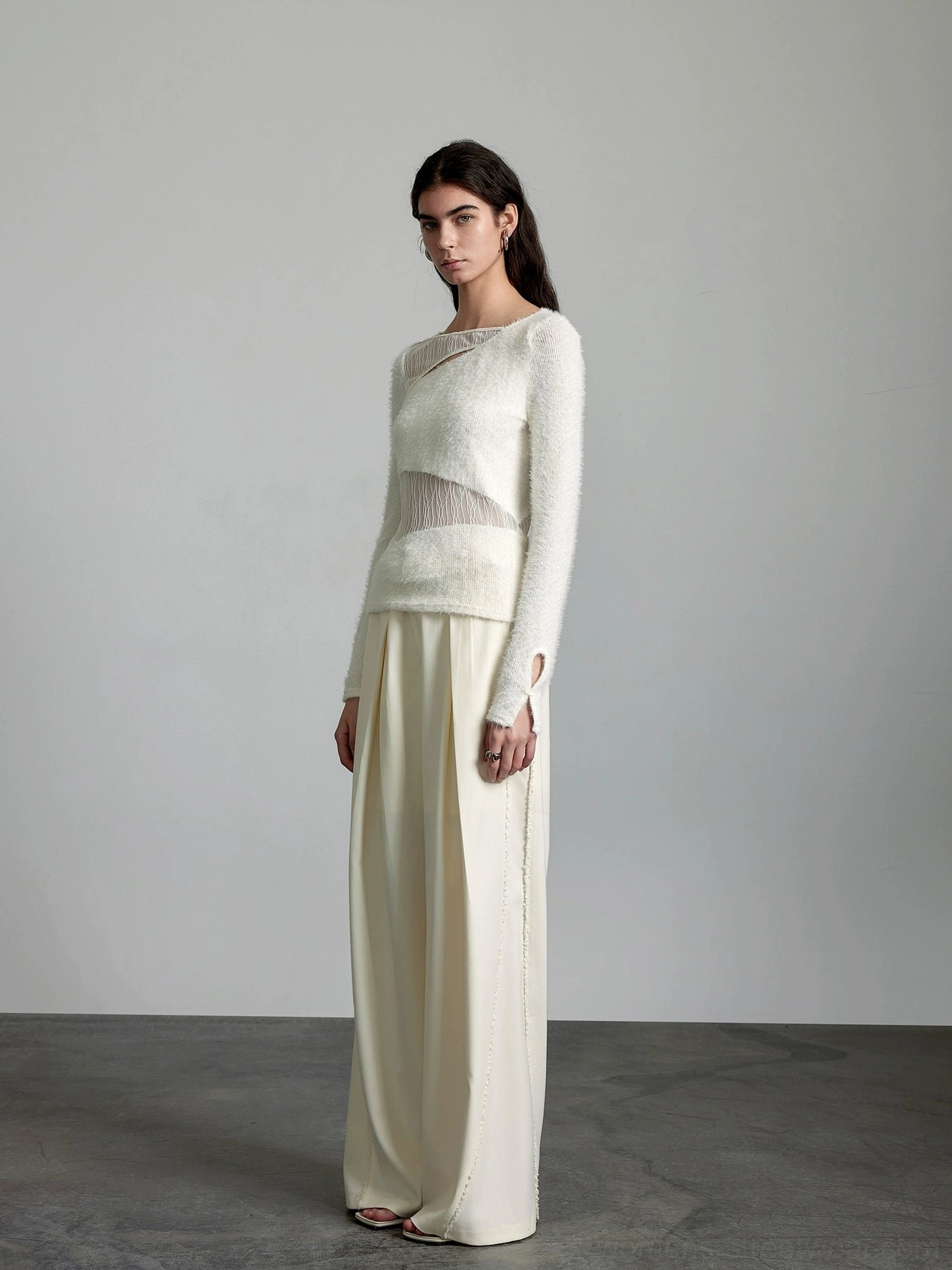 Full front view of off-white high-waisted wide-leg trousers with front pleats and smooth matte fabric