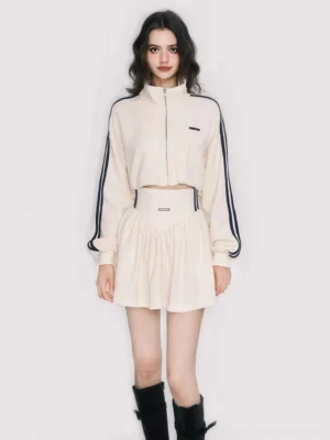 Off-white cropped zip track jacket and navy striped pleated mini skirt tennis-core outfit front view