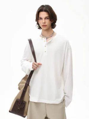 Off white oversized long sleeve Henley tee with relaxed shoulders and half button neckline on a male model