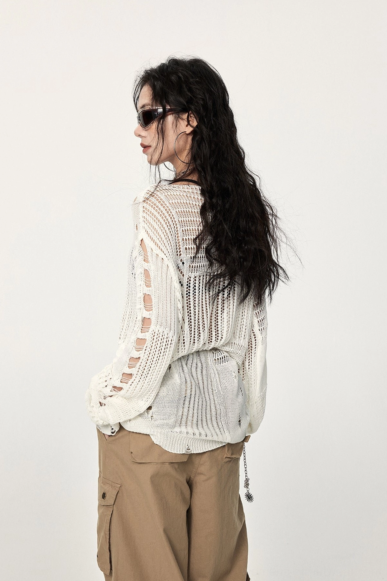 Back and side view of an off-white oversized distressed crochet sweater with sleeve cut-outs, open knit construction, and asymmetric streetwear silhouette