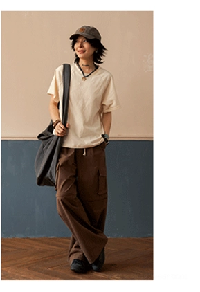 Warm off-white raglan sleeve t-shirt full body front styling with flat cap and canvas tote bag, paired with brown cargo pants