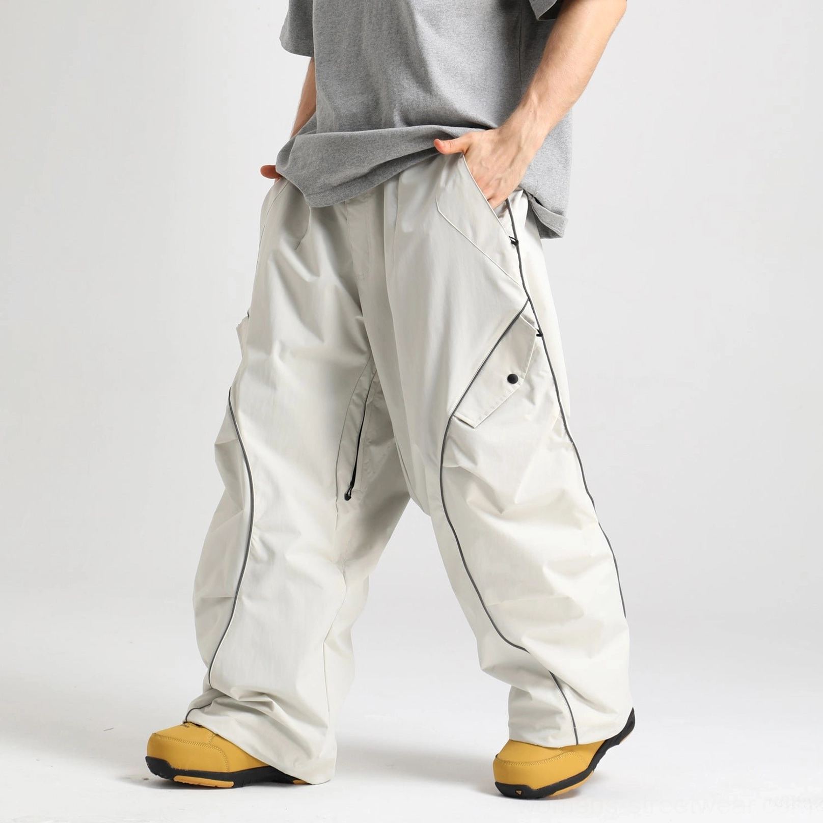 Off white reflective piped baggy snowboard cargo pants shown in a side-front view with oversized wide legs