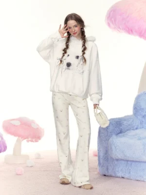 Model wearing an off-white oversized dog print hoodie with rhinestone graphic, fuzzy hood trim, and relaxed streetwear styling in a whimsical plush studio