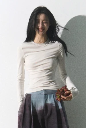 Model wearing an off-white slim fit ribbed crew neck long sleeve streetwear top in a minimalist studio