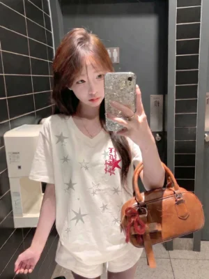 Close-up view of an off-white women's streetwear V-neck T-shirt showing gray star prints and contrasting red chest artwork