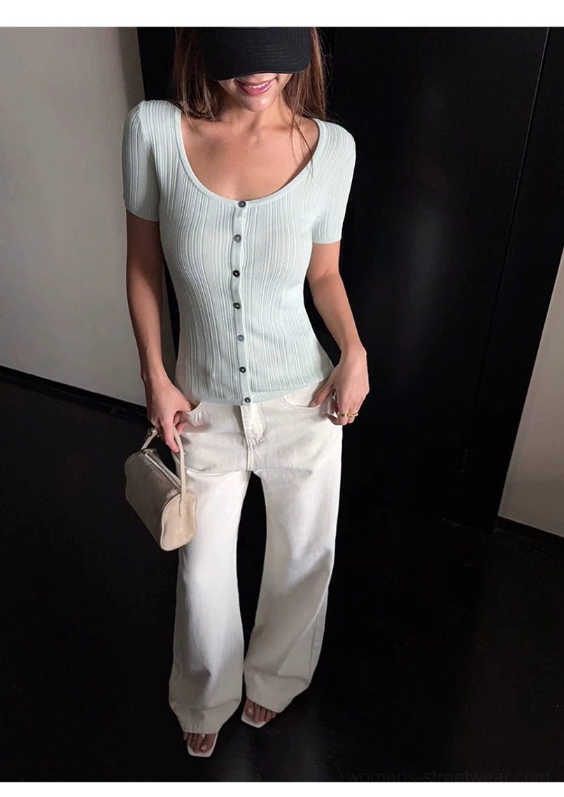 Three-quarter studio view of off-white wide-leg denim pants styled with a fitted mint ribbed button-up top and beige mini handbag
