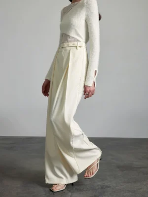Side walking view of off-white wide-leg streetwear pants with a flowing tailored fit and high waist