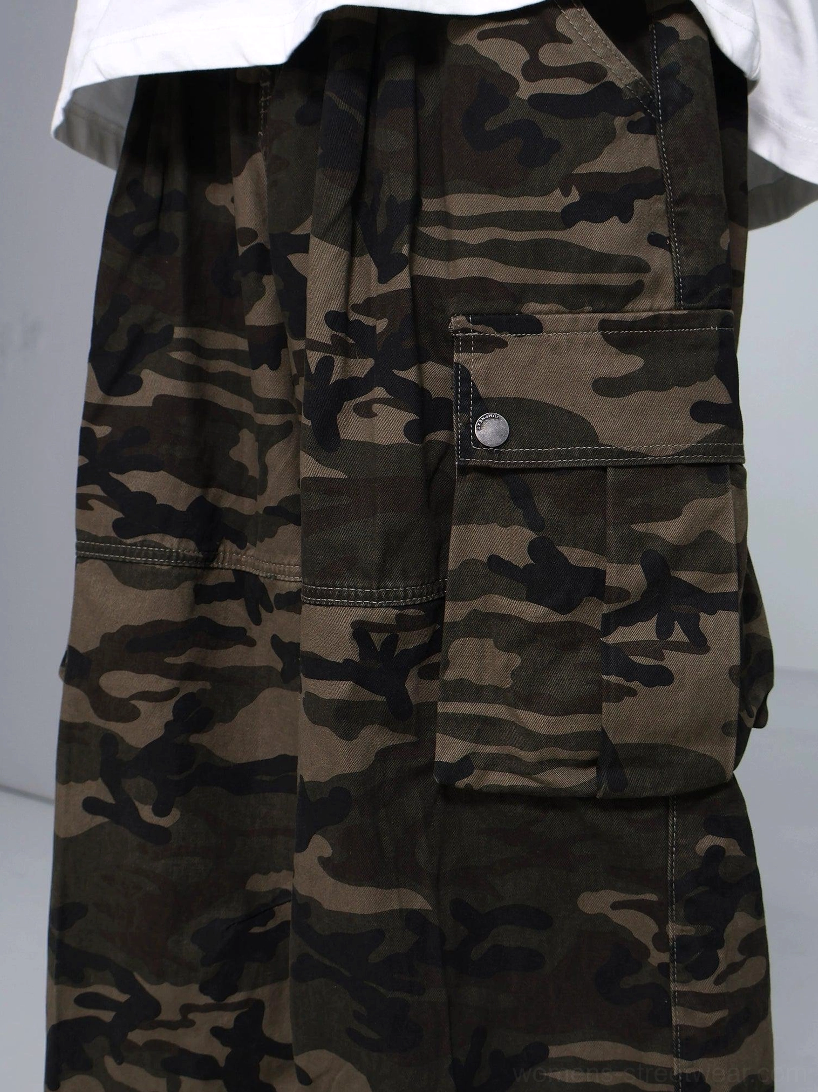 Close-up of the pleated elastic waistband and button-fastened side cargo pocket on durable olive camouflage streetwear pants