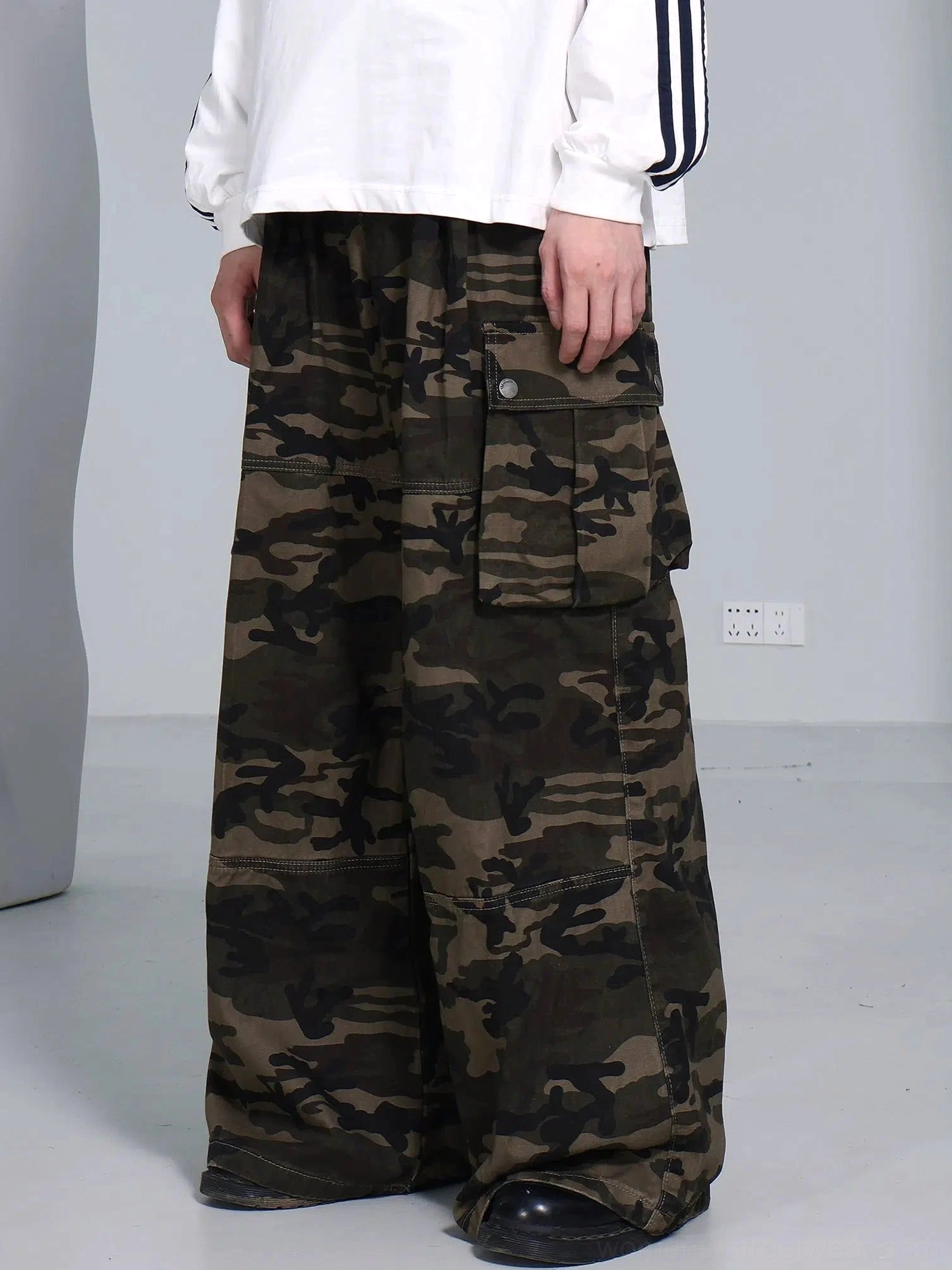 Close view of relaxed olive camouflage streetwear cargo pants showing the buttoned cargo pocket and elasticated waistband