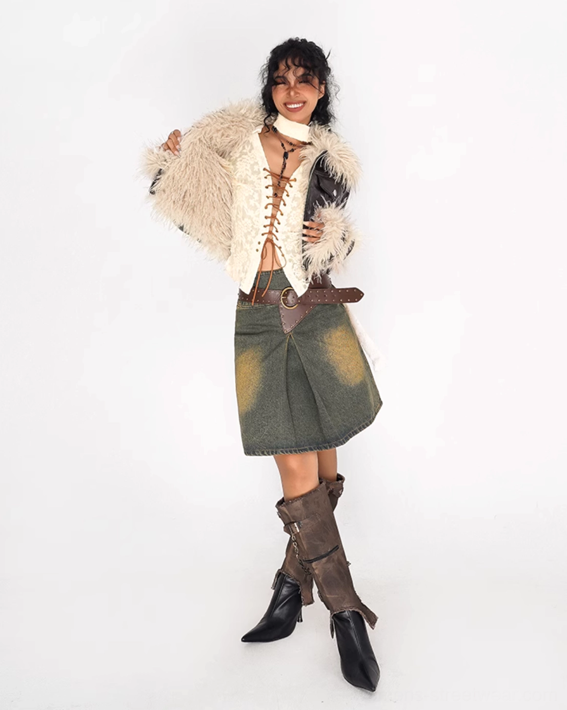 Three-quarter side view of an olive distressed denim mini skirt with A-line shape, brown belt, fur-trimmed jacket, and heeled boots