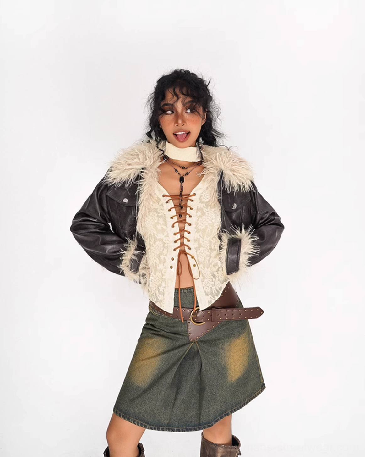 Front view of olive green distressed denim mini skirt with brown leather belt detail styled with a lace top and leather jacket