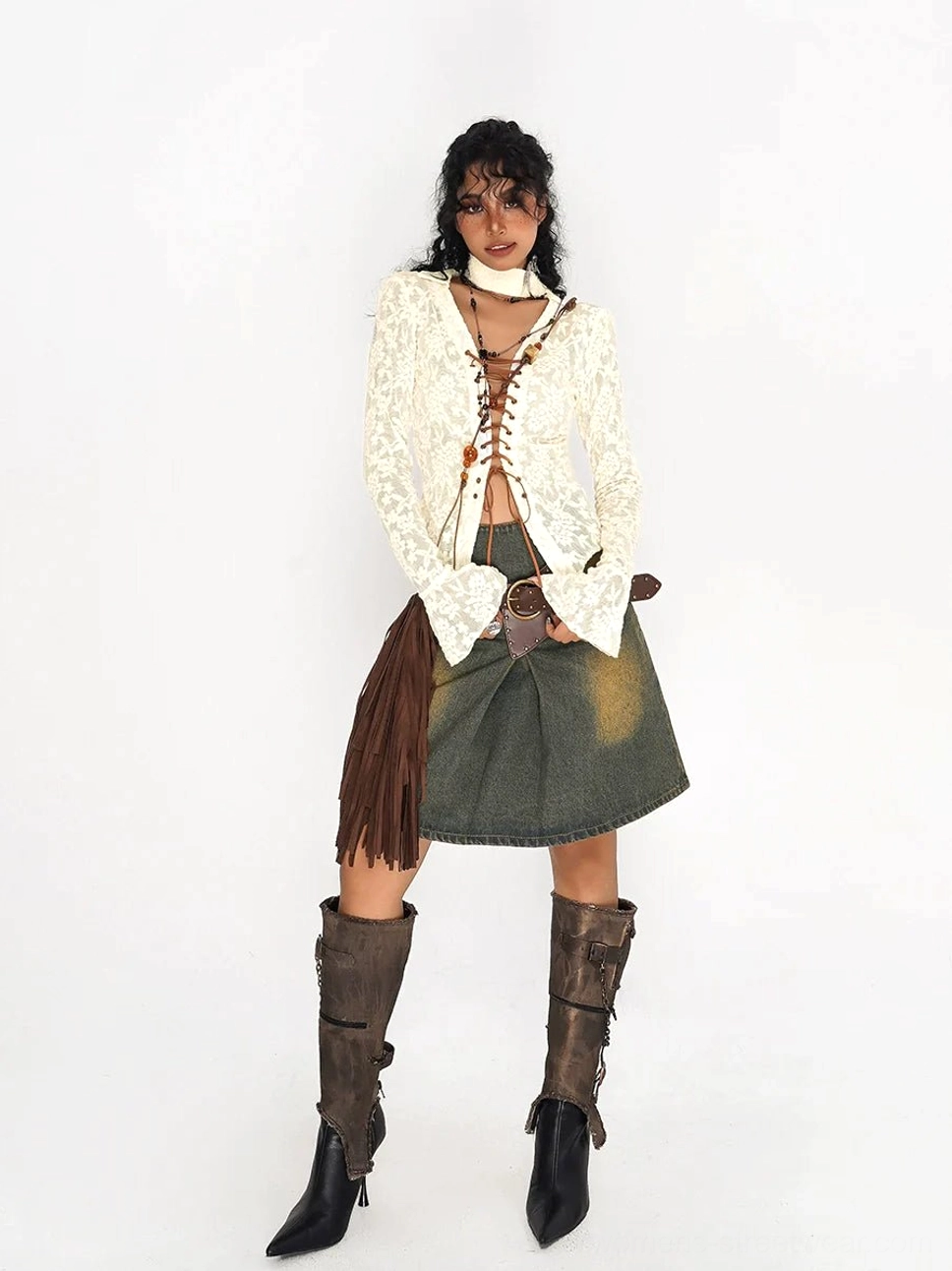 Olive green distressed denim mini skirt with western belt detail styled with a cream lace top and fringe bag in a festival streetwear look