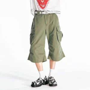 Front full-body view of olive green flared utility cargo Bermuda shorts with oversized thigh pockets, wide cropped legs, a relaxed fit, white graphic T-shirt, white crew socks, and cow-print loafers