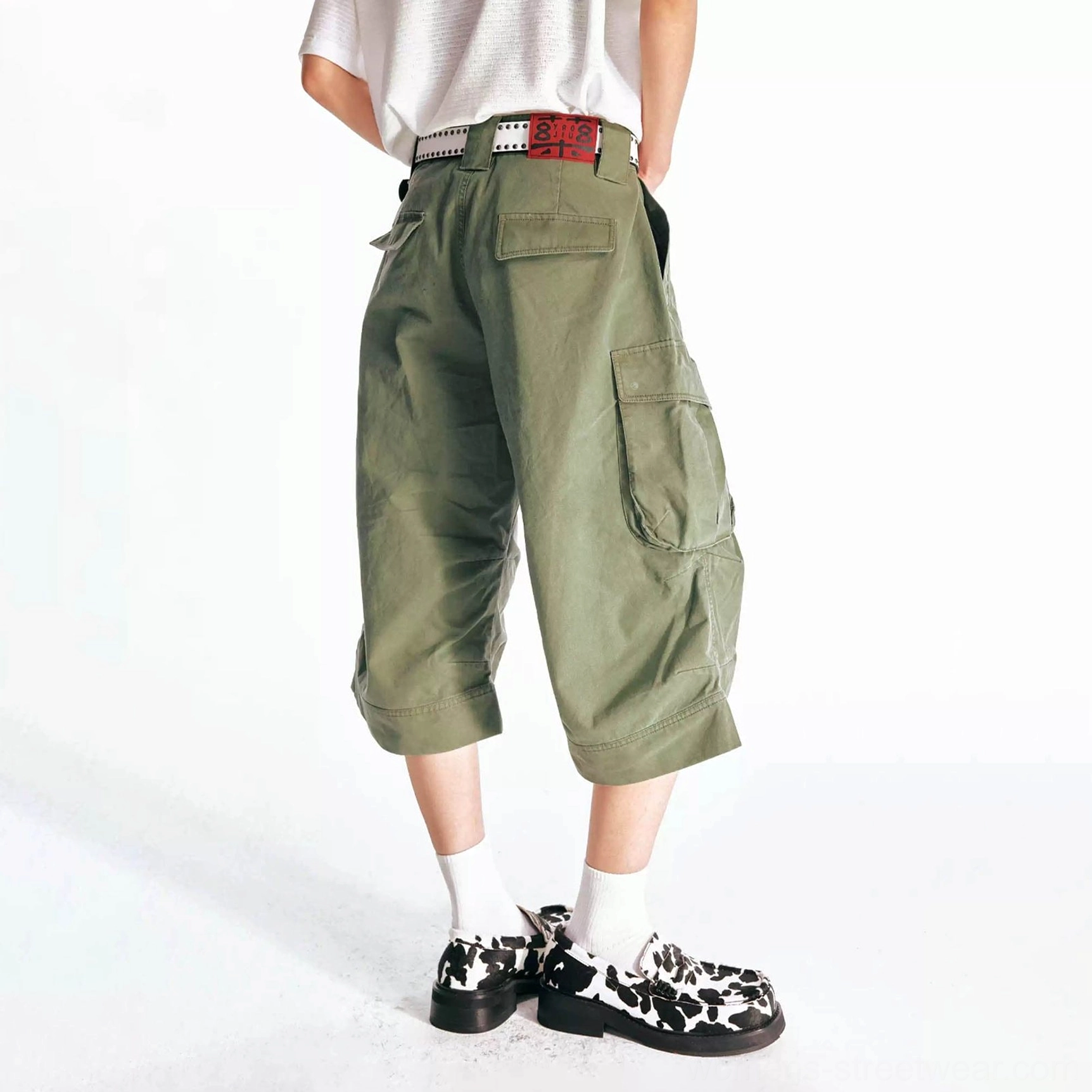 Back three-quarter view of olive green oversized cargo Bermuda shorts showing the relaxed flared silhouette, back patch pocket, waistband detail, and cropped hem