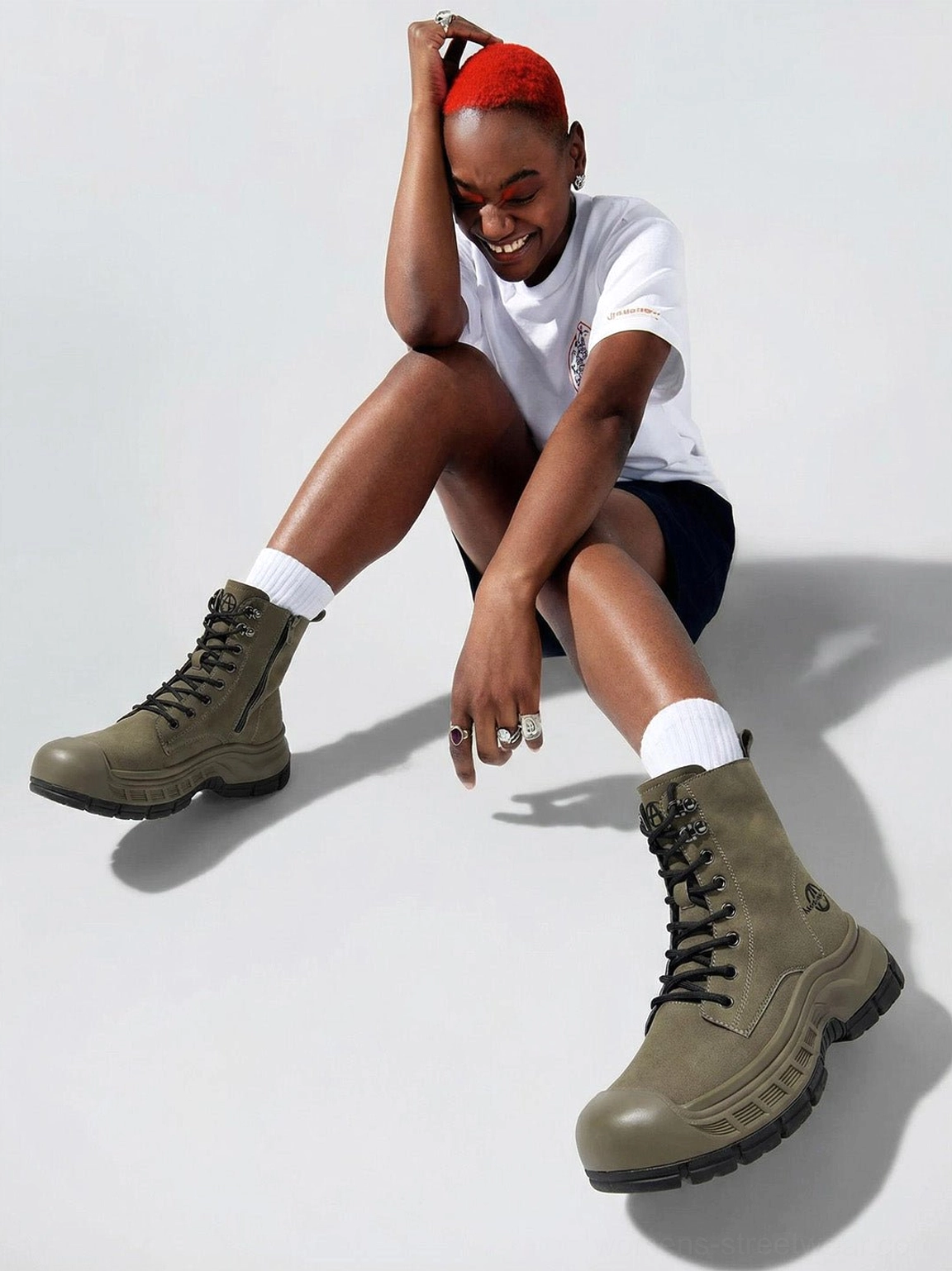 Olive green platform combat boots worn by seated model showing chunky black outsole and side profile