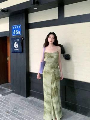Olive Green tie-dye spaghetti strap maxi slip dress with square neck, detachable wrap waist sash, floor-length silhouette, and purple shoulder bag on a Japanese-style street