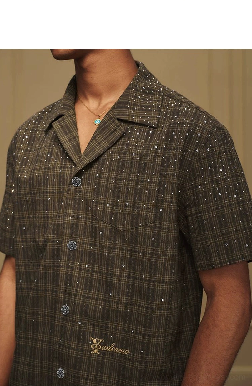 Close-up front view of olive rhinestone plaid camp collar shirt showing buttons pocket and embroidered script detail