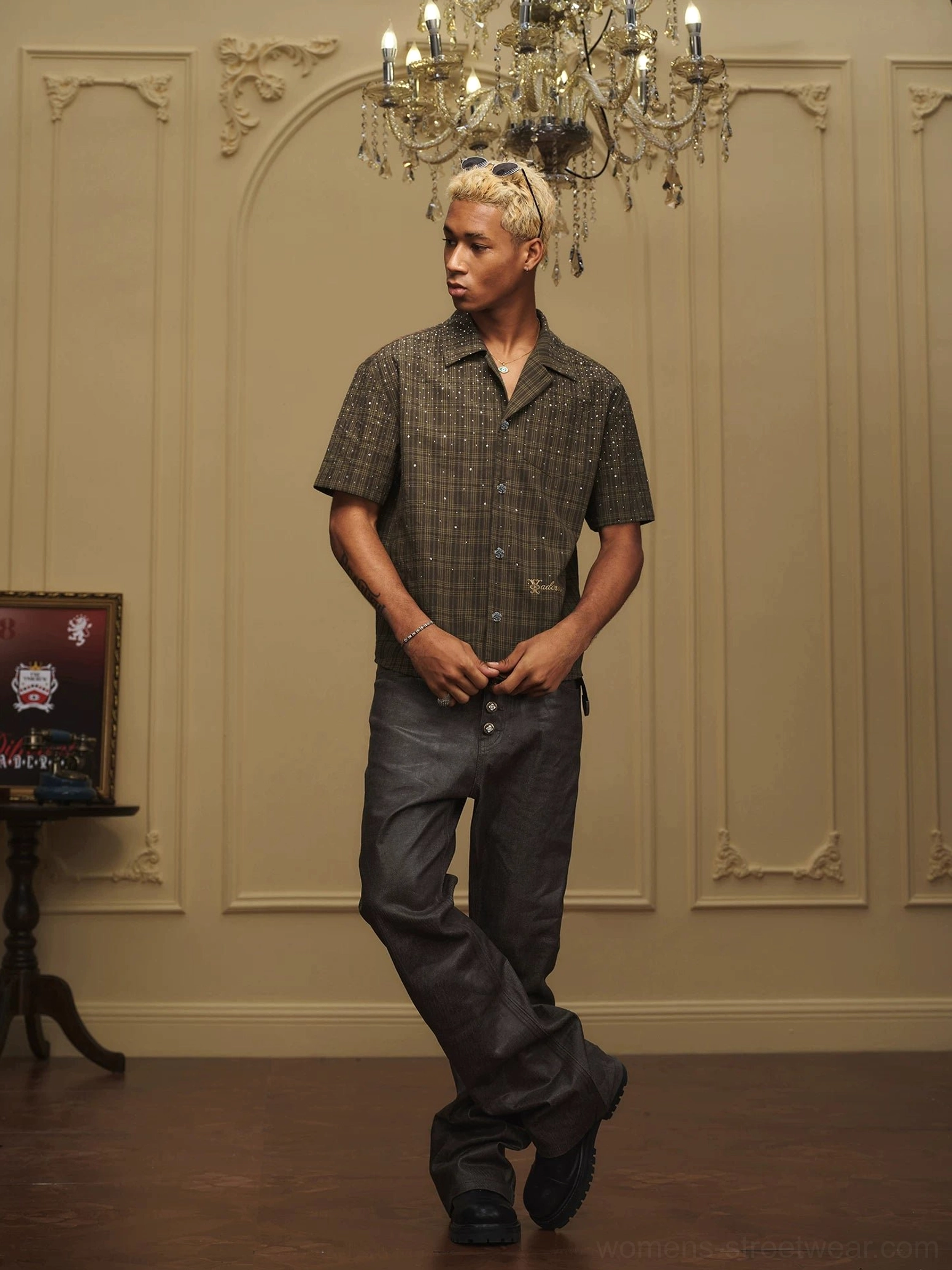 Front full body view of olive rhinestone plaid camp collar streetwear shirt styled with dark wide leg trousers