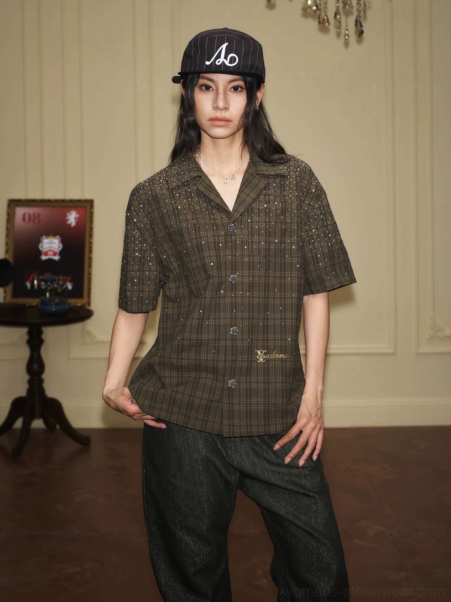 Olive rhinestone plaid camp collar shirt on female model with cap and dark wide leg denim streetwear styling