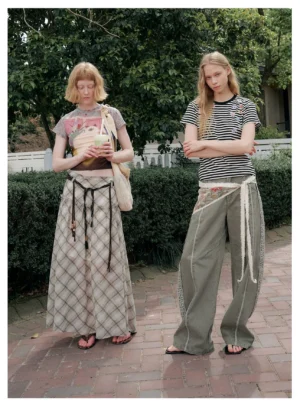 Olive wide-leg streetwear cargo pants shown on two models outdoors, featuring washed green denim, decorative tapestry side panels, and layered drawstring waist details