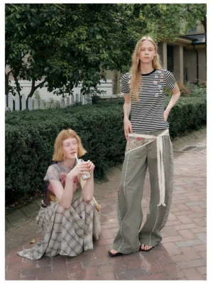 Olive tapestry wide-leg streetwear pants styled on multiple models in a casual outdoor setting with relaxed utility-inspired silhouettes