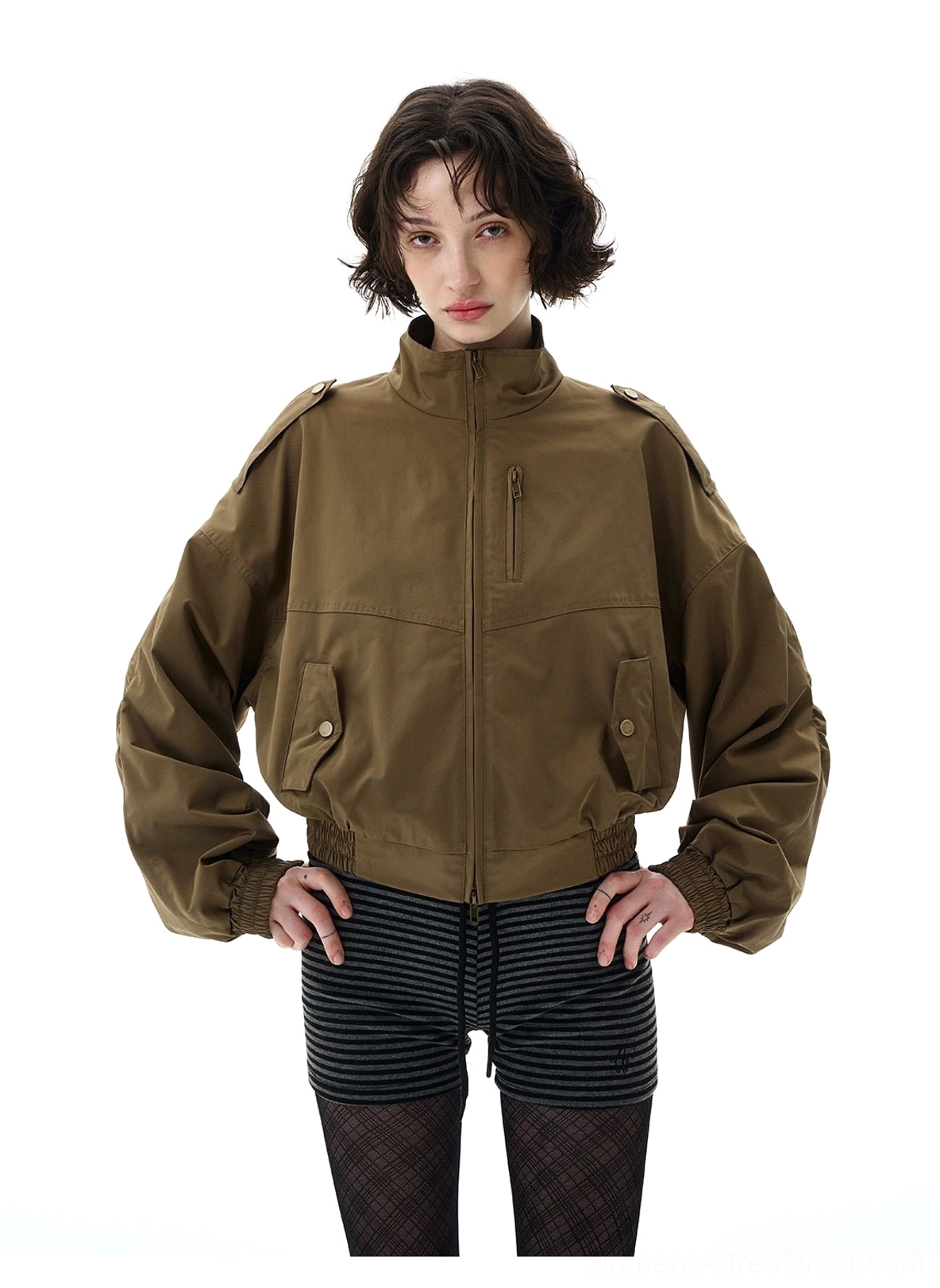 Close-up of cropped olive green bomber jacket showing front zipper, snap chest pockets, shoulder epaulets, and elastic waist hem