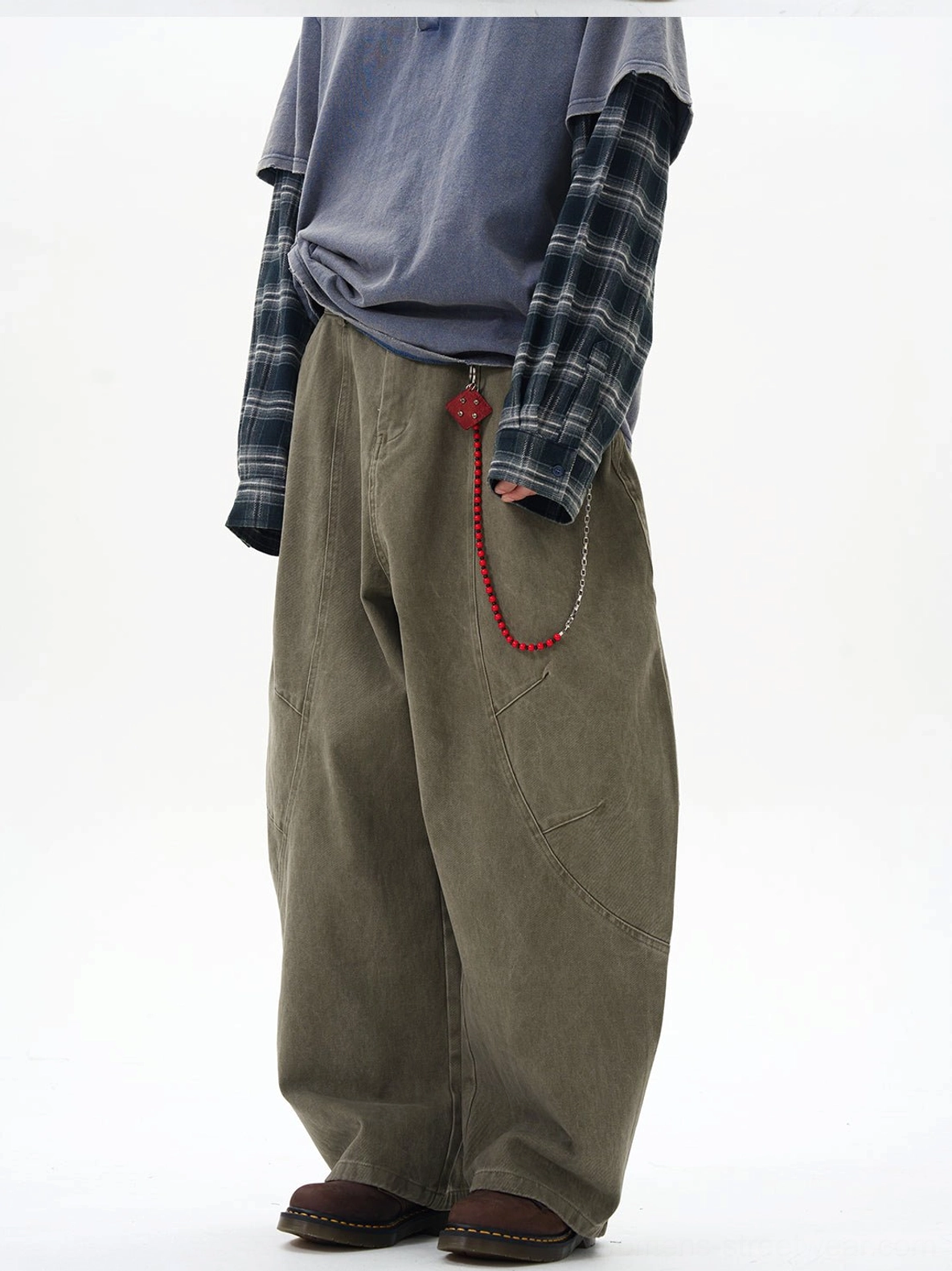 Side view of relaxed olive cargo pants featuring curved cargo pocket stitching and decorative red chain detail