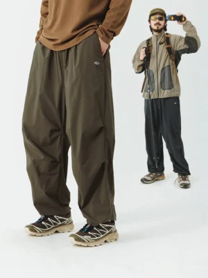 Models wearing olive green wide-leg outdoor cargo pants with a color-block tactical jacket and backpack for a hiking streetwear outfit