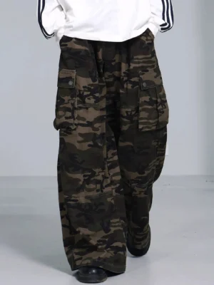 Olive woodland camouflage wide leg cargo pants styled with a white striped long sleeve shirt and black leather shoes in a streetwear outfit
