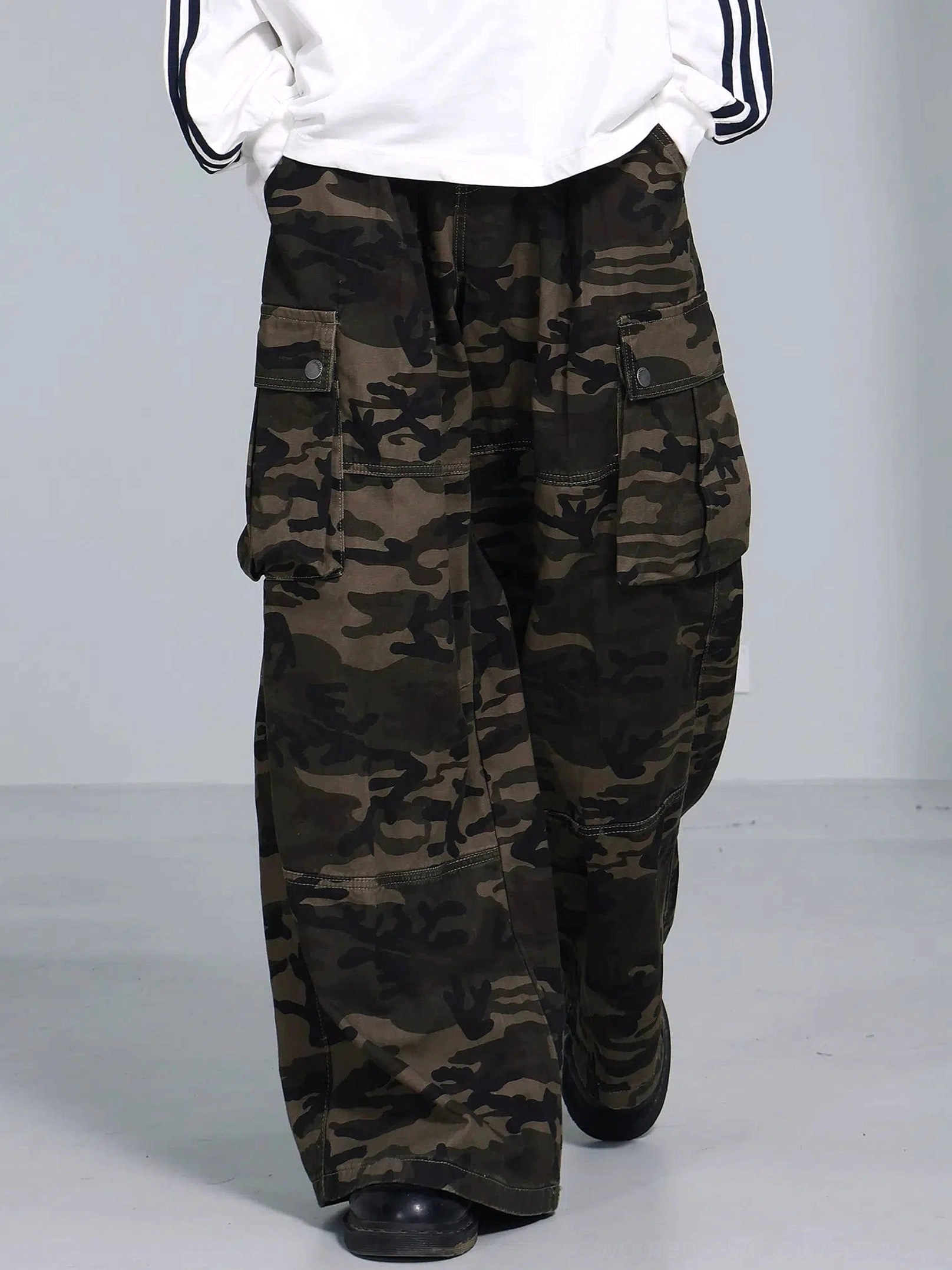 Olive woodland camouflage wide leg cargo pants styled with a white striped long sleeve shirt and black leather shoes in a streetwear outfit