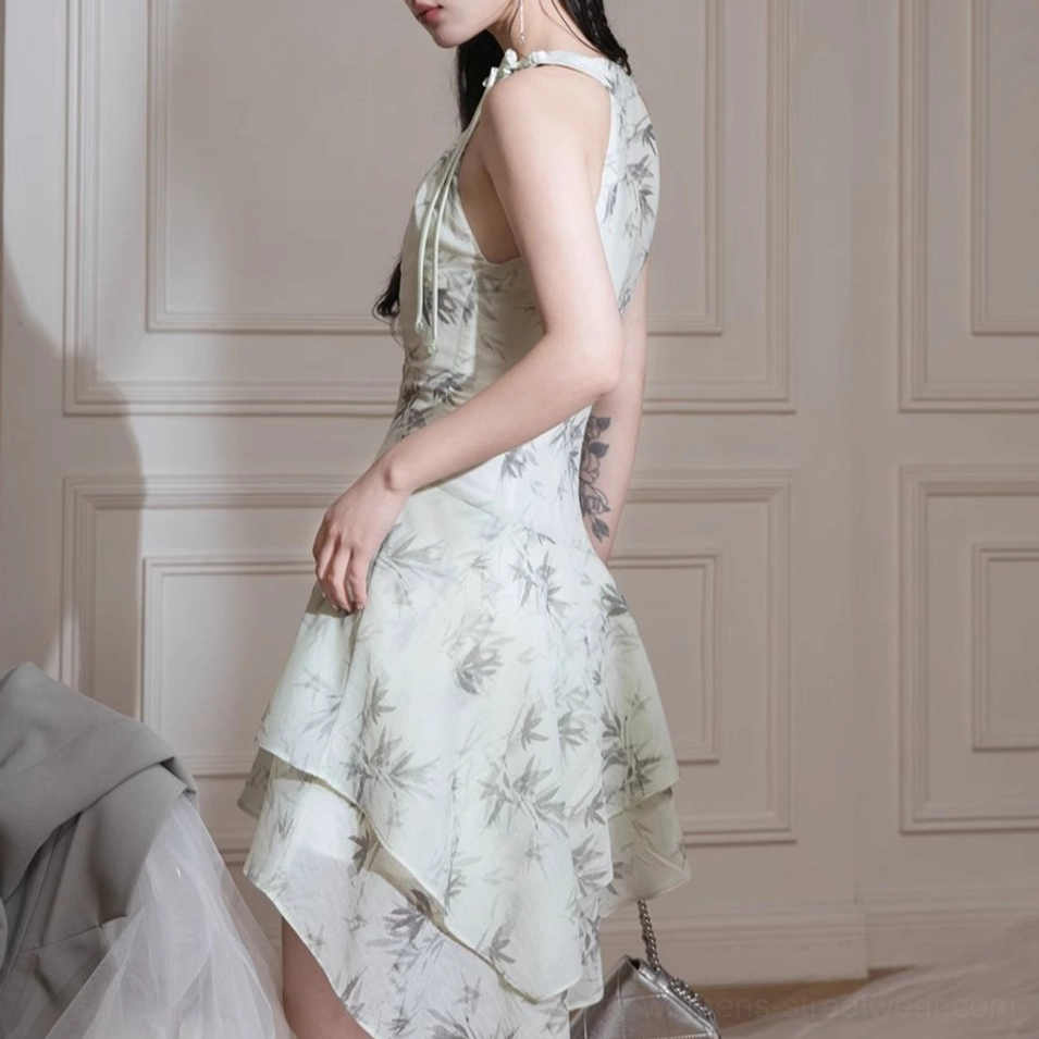 Side rear view showing the open back halter neckline and asymmetric ruffled hem of an ink bamboo print midi dress