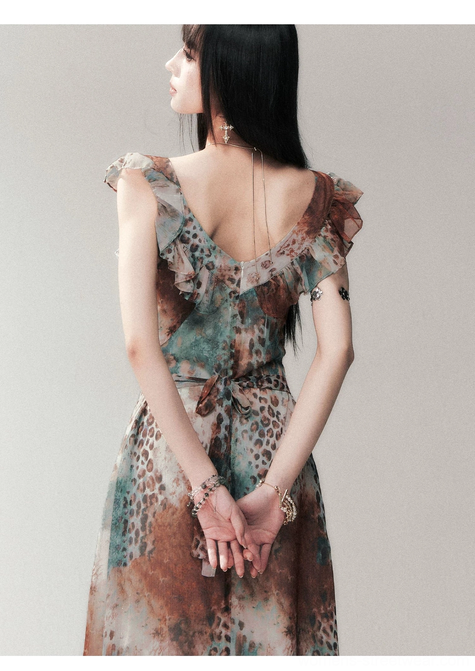 Back view of an open-back leopard print maxi dress with ruffled shoulder straps, tied waist sash, and full-length printed skirt