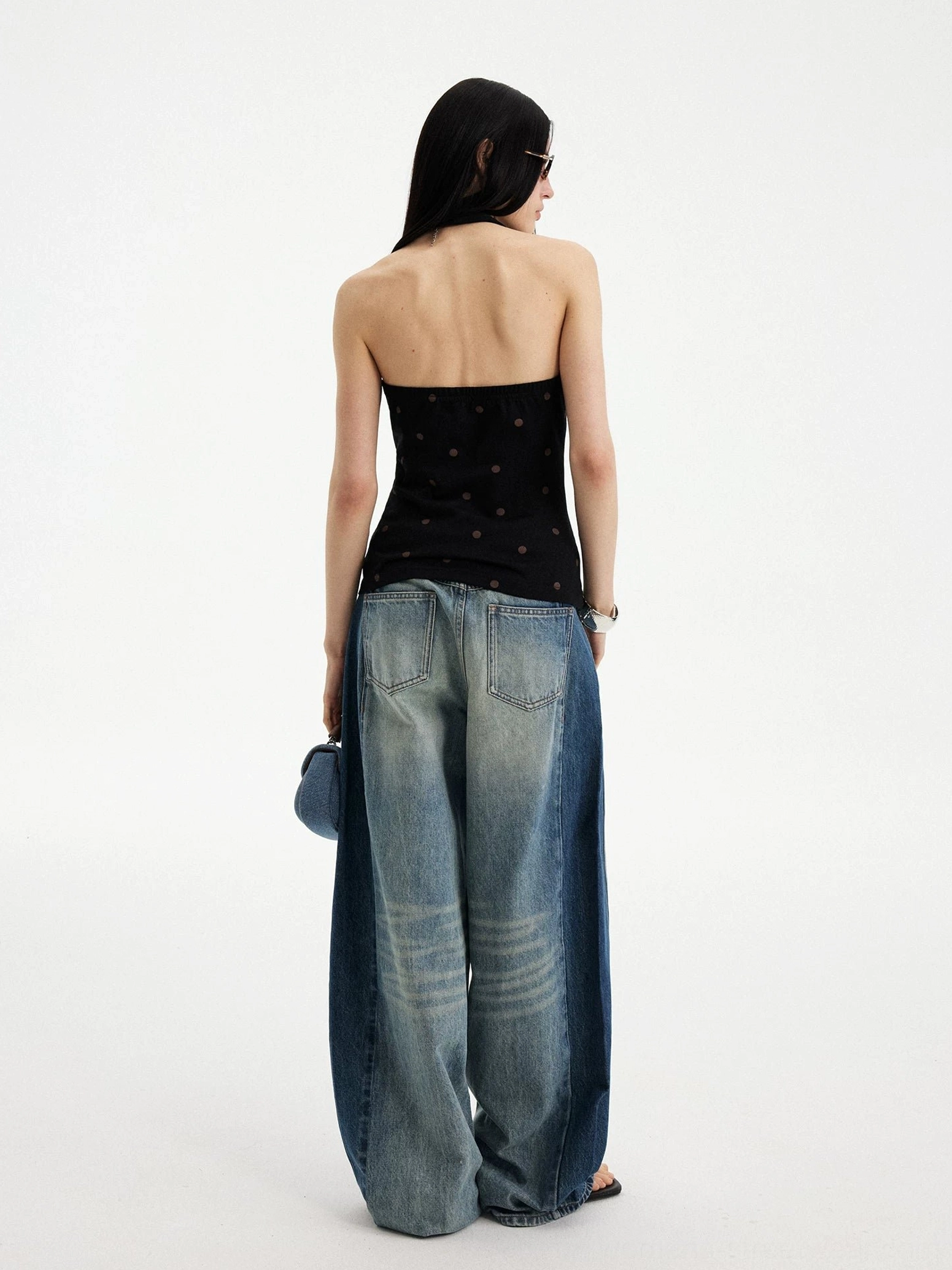 Back view of a black and brown polka dot puppy print halter top showing the open back silhouette styled with wide leg jeans