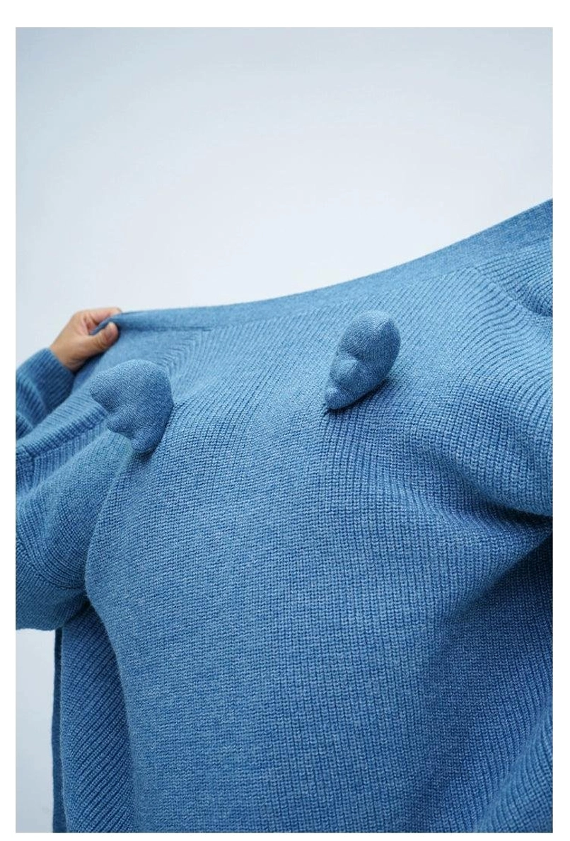 Close-up of denim blue fuzzy ribbed knit cardigan angel wing and pom-pom back decoration