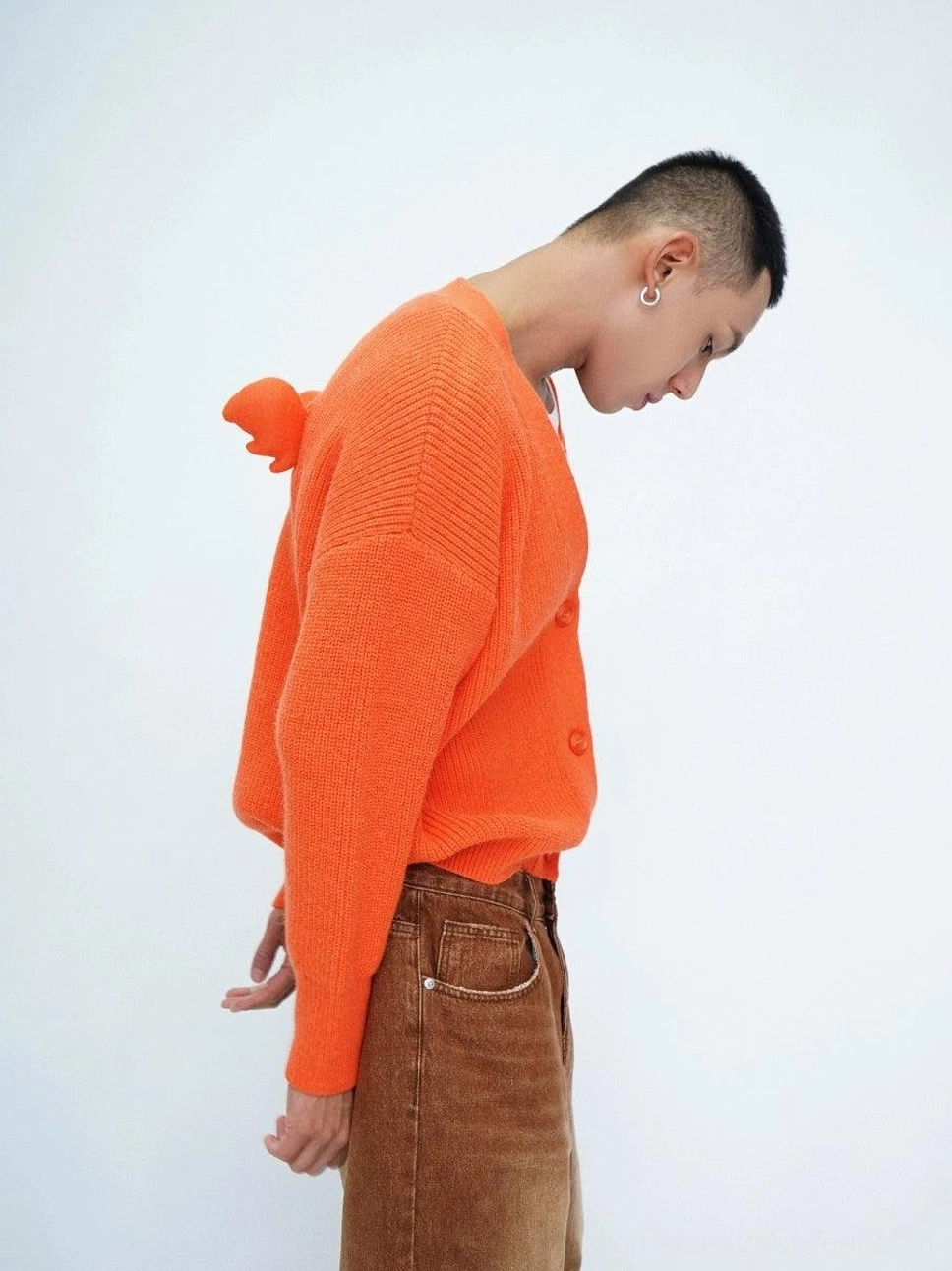 Orange oversized pom-pom fuzzy knit cardigan side profile with button front and drop shoulders