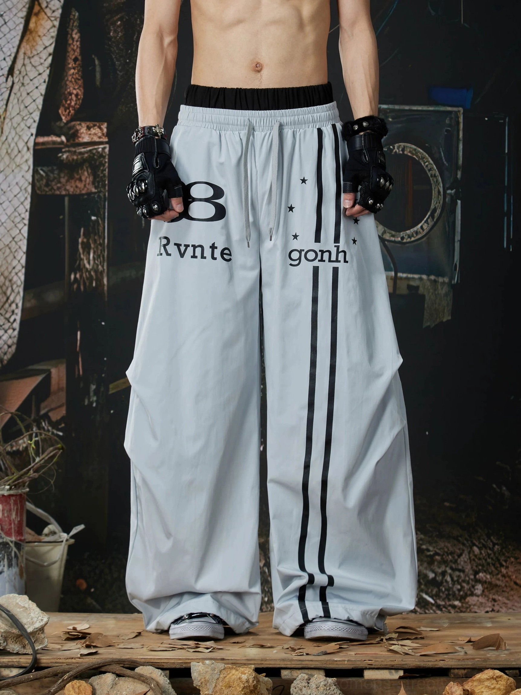 Light gray oversized Astro Stripe track pants with black racing stripes, varsity number graphics, wide-leg streetwear fit, and elastic drawstring waistband
