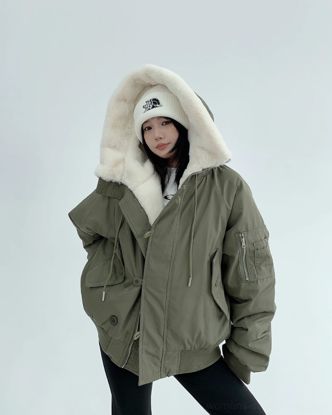 Oversized army green aviator bomber jacket worn with the hood up, featuring an off-white faux-fur trim and button placket