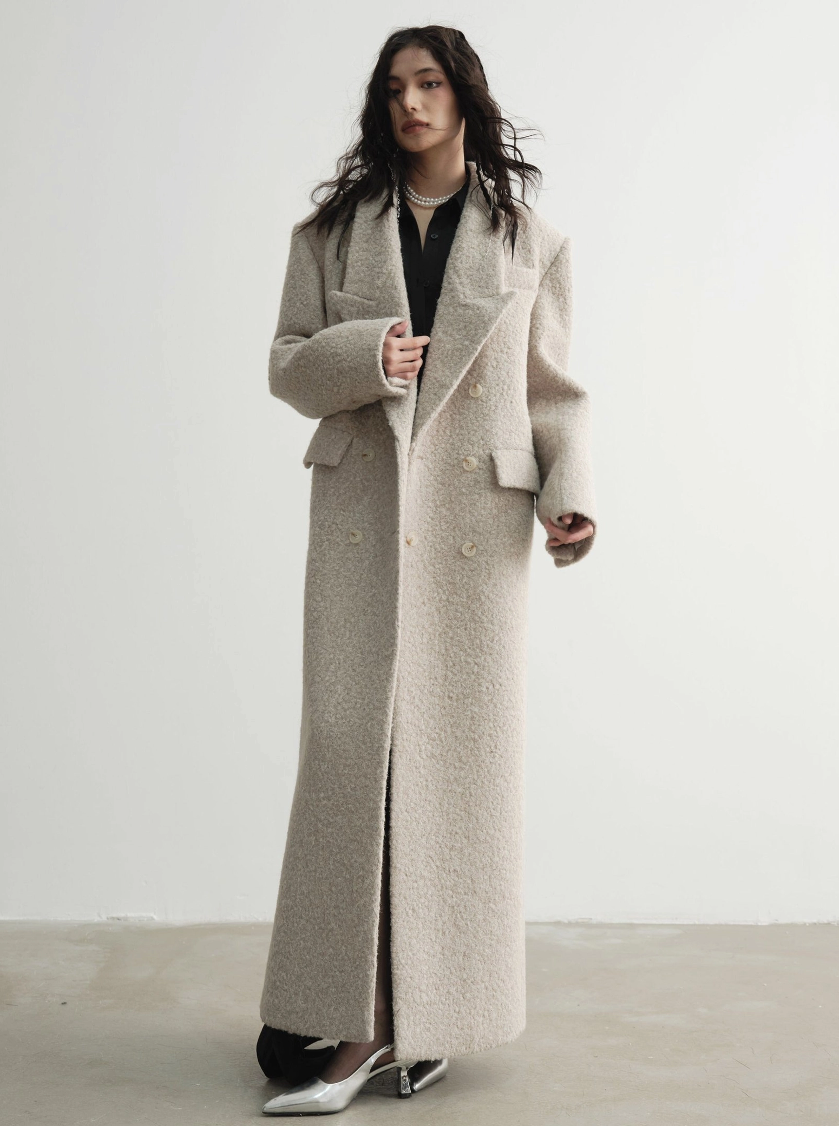 Full front view of an oversized beige wool maxi coat with straight tailored silhouette, button closure and front pockets