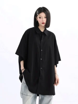Side view of a women's oversized black button-up shirt with dropped sleeves pointed collar and curved hem