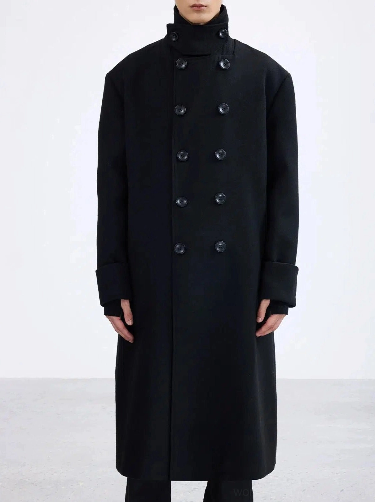 Front view of an oversized black double-breasted long overcoat with structured collar, wide cuffs, and minimalist Seoul streetwear styling