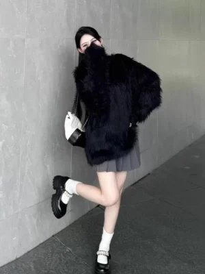 Black oversized faux fur crewneck sweater styled with a pleated mini skirt on an urban streetwear model