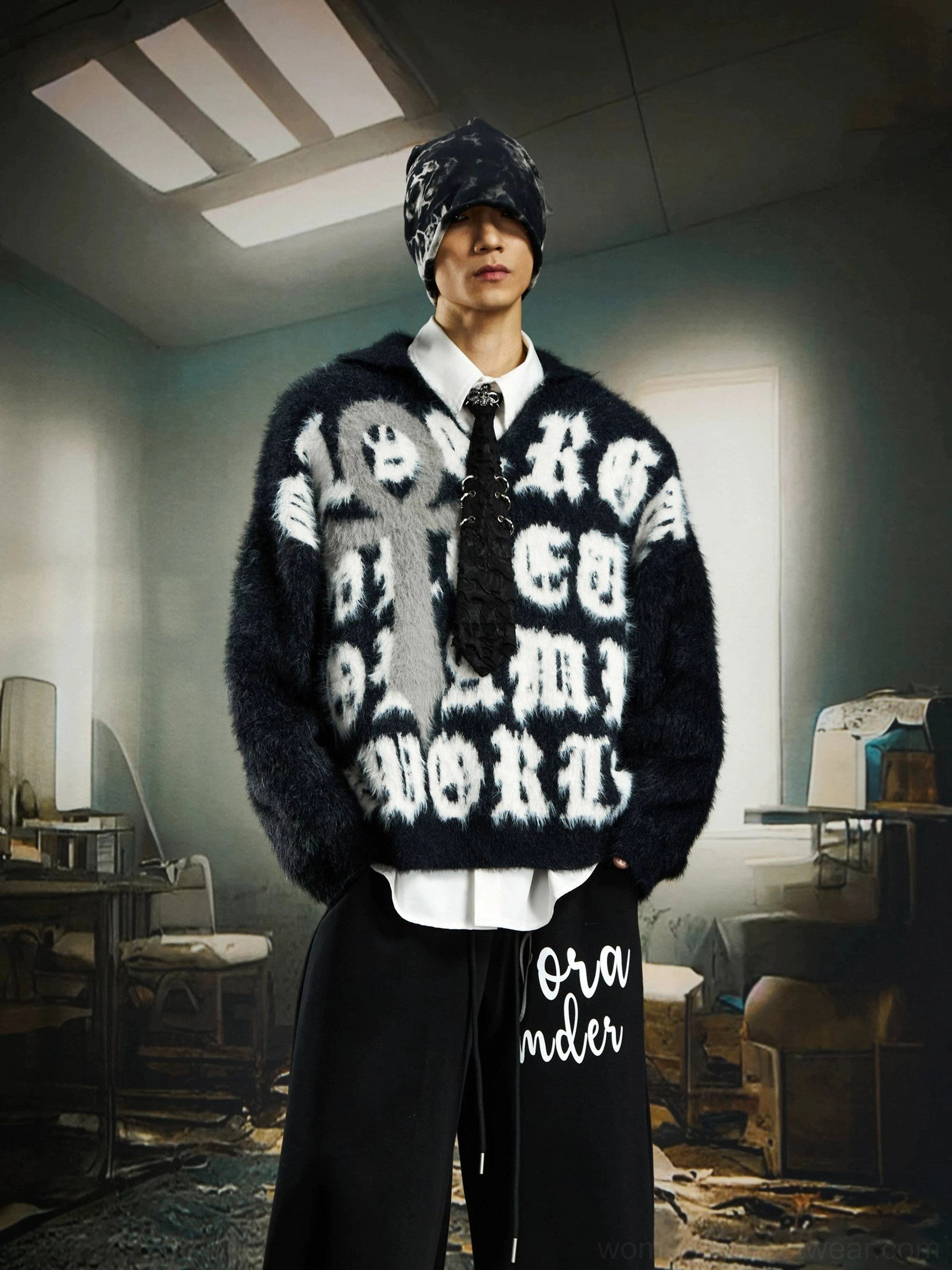 Black oversized gothic cross knit sweater with white lettering worn with a beanie, white shirt, tie, and relaxed streetwear trousers