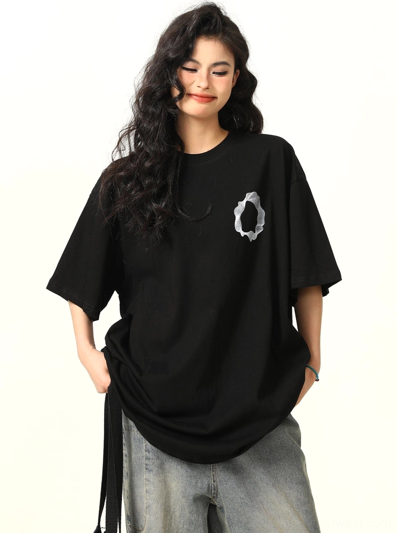 Three quarter front view of black oversized graphic cotton t shirt showing adjustable side drawstring hem detail