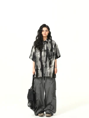 Full body view of oversized monochrome watercolor print shirt styled with gray wide-leg cargo pants and black tote bag
