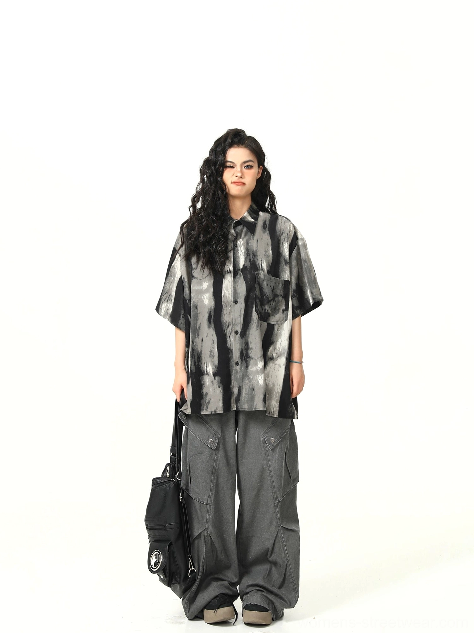 Full body view of oversized monochrome watercolor print shirt styled with gray wide-leg cargo pants and black tote bag